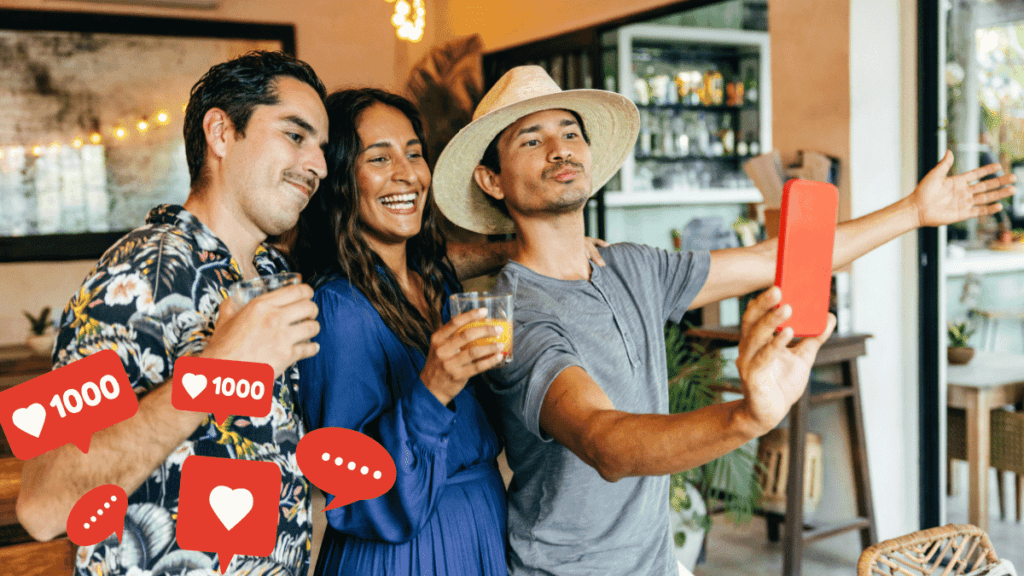 Três amigos sorridentes tirando uma selfie em um bar, segurando bebidas e simulando curtidas e interações nas redes sociais.